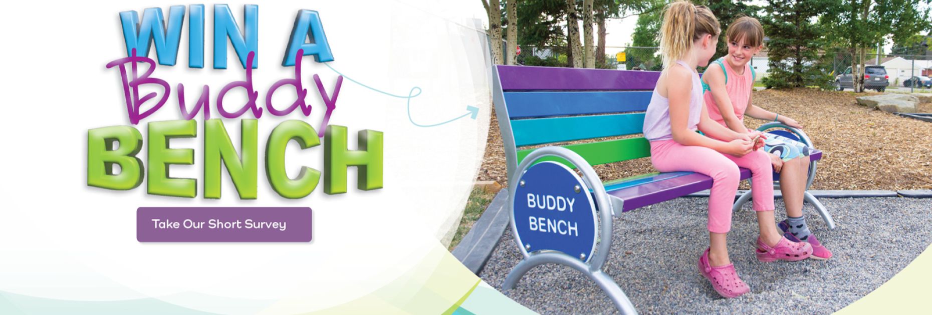 two girls sitting on a colourful bench with the words Buddy Bench