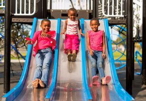 three girls enjoying the thrill of sliding down the exciting Blue Imp Triple Dip stainless steel slide