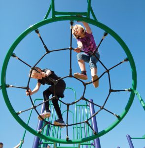 kids climbing on round rope climber against the sky